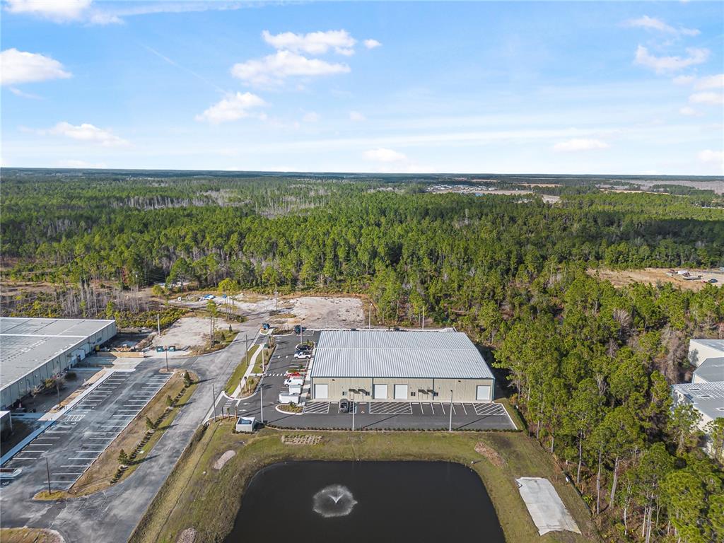 An aerial view shows a commercial warehouse building with a parking lot and a pond — 24 HARGROVE GRADE, PALM COAST, FL