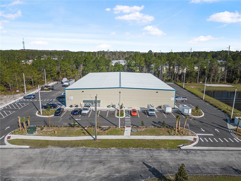 An aerial view of a metal warehouse building with a surrounding parking lot and trees — 24 HARGROVE GRADE, PALM COAST, FL