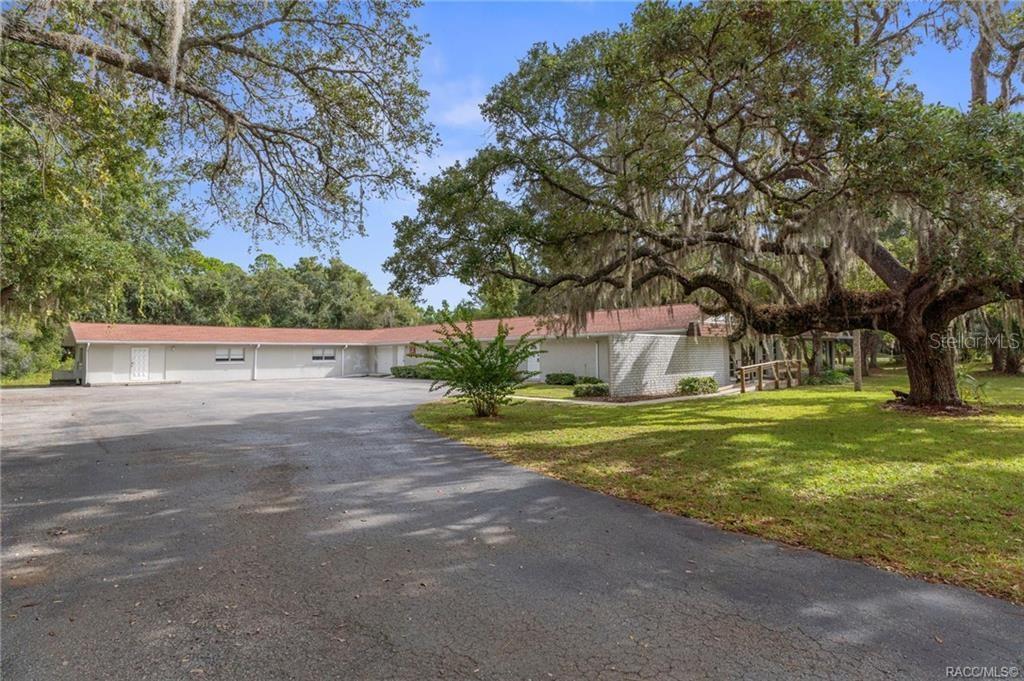 A long, single-story building with a red roof sits behind a large paved parking lot — 377 HIGHWAY 40 W, INGLIS, FL