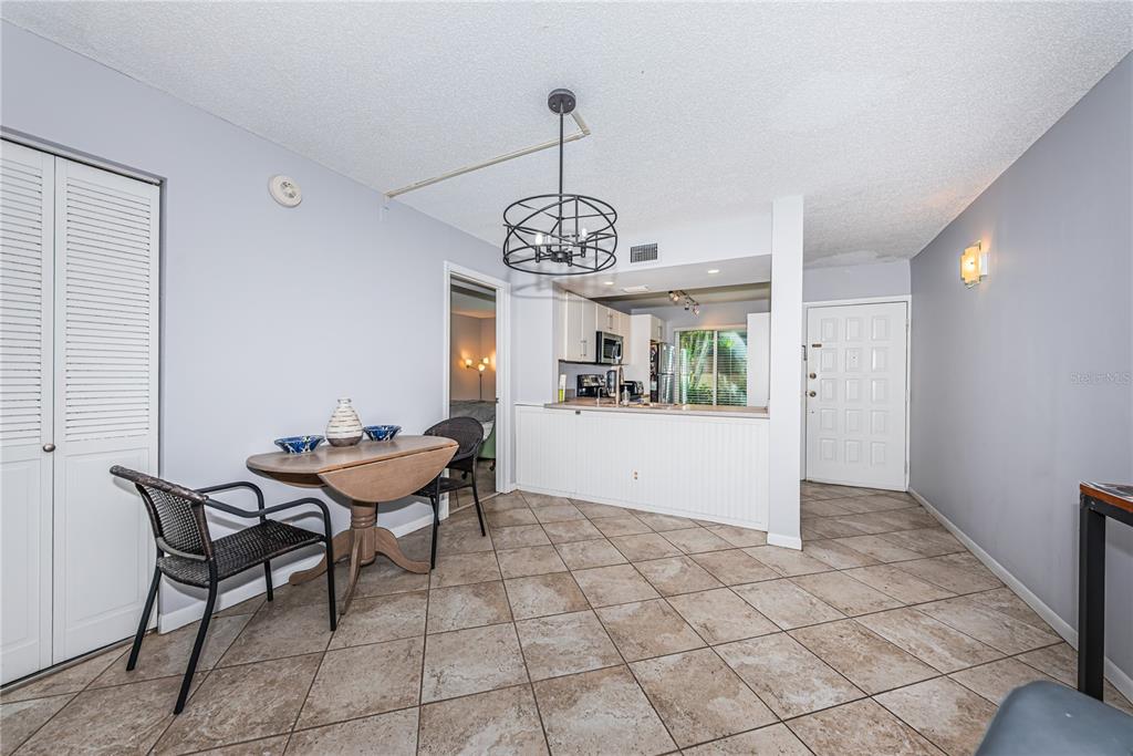 A dining area with a drop-leaf table sits adjacent to an open kitchen with tile flooring — 6269 PALMA DEL MAR BOULEVARD S UNIT 112, ST PETERSBURG, FL
