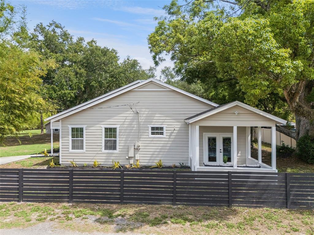 A light-colored, single-story house with horizontal siding and a screened porch behind a fence — 1825 DEMASTUS LANE, OCOEE, FL