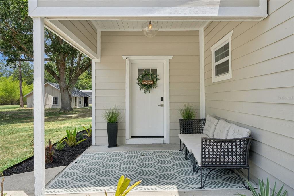 A beige house with a stone patio, fire pit, and black horizontal fence in the backyard — 1825 DEMASTUS LANE, OCOEE, FL