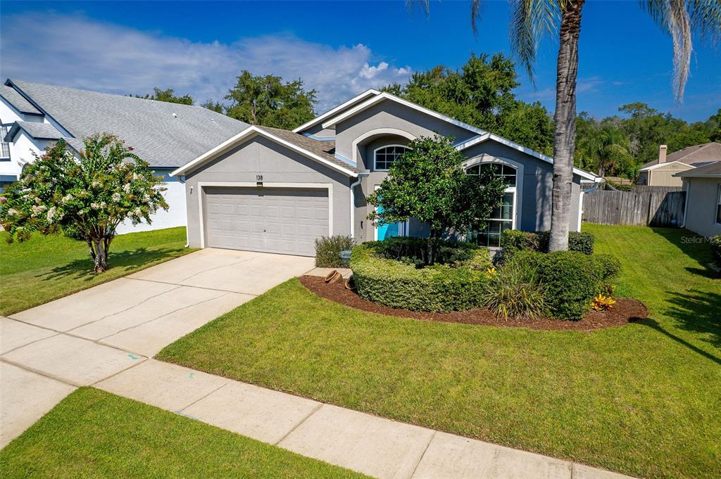 A single-story suburban house features a gray exterior, a two-car garage, and a landscaped yard — 138 BRIGHTVIEW DRIVE, LAKE MARY, FL