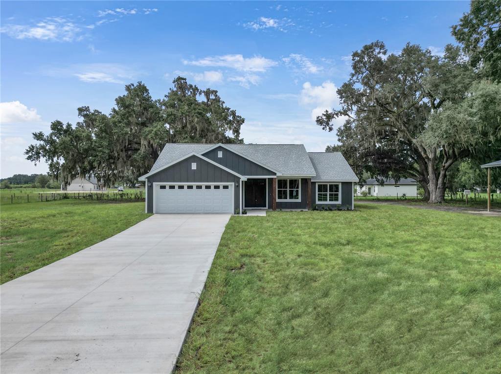 A single-story house with dark gray siding, a two-car garage, and a concrete driveway — 1173 W C 476, BUSHNELL, FL