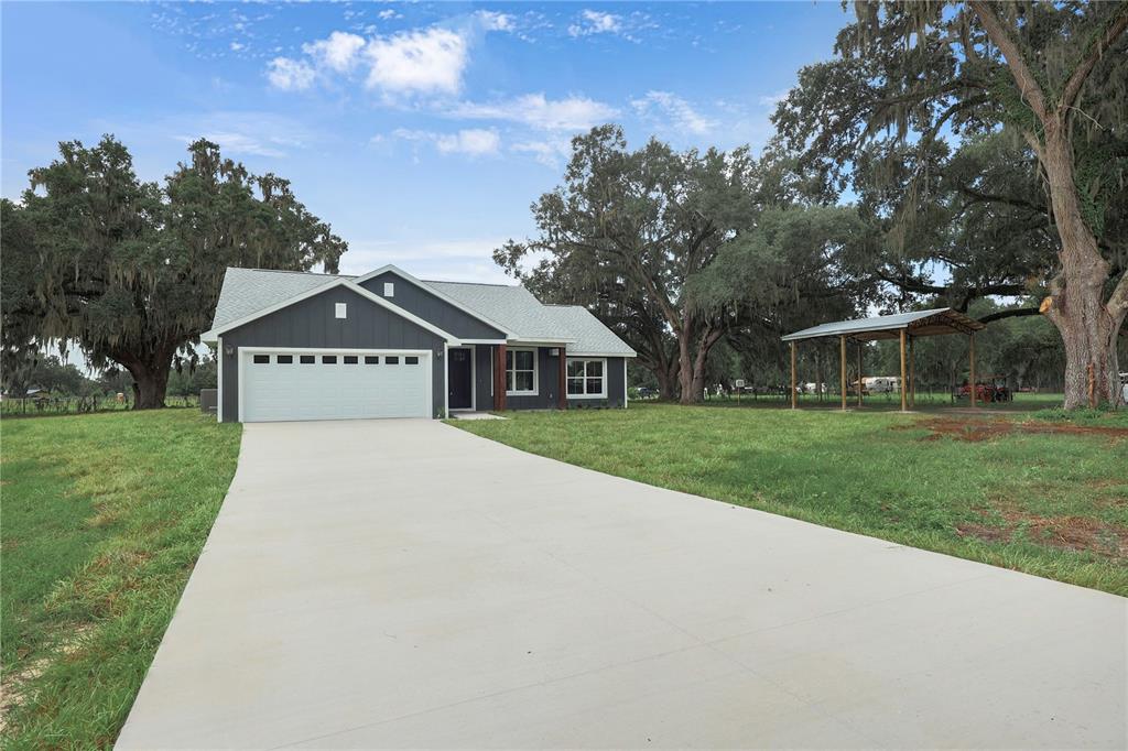 A dark gray house with a white garage door and a separate metal carport — 1173 W C 476, BUSHNELL, FL