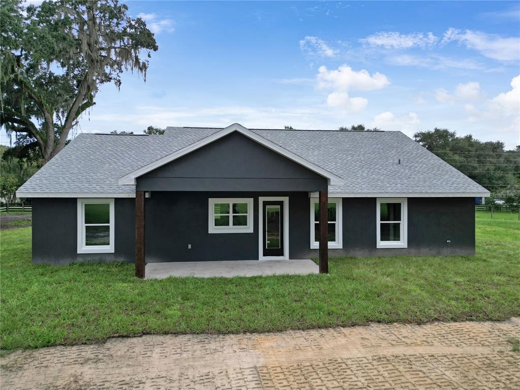 A dark gray single-story house with a covered porch and white-trimmed windows — 1173 W C 476, BUSHNELL, FL