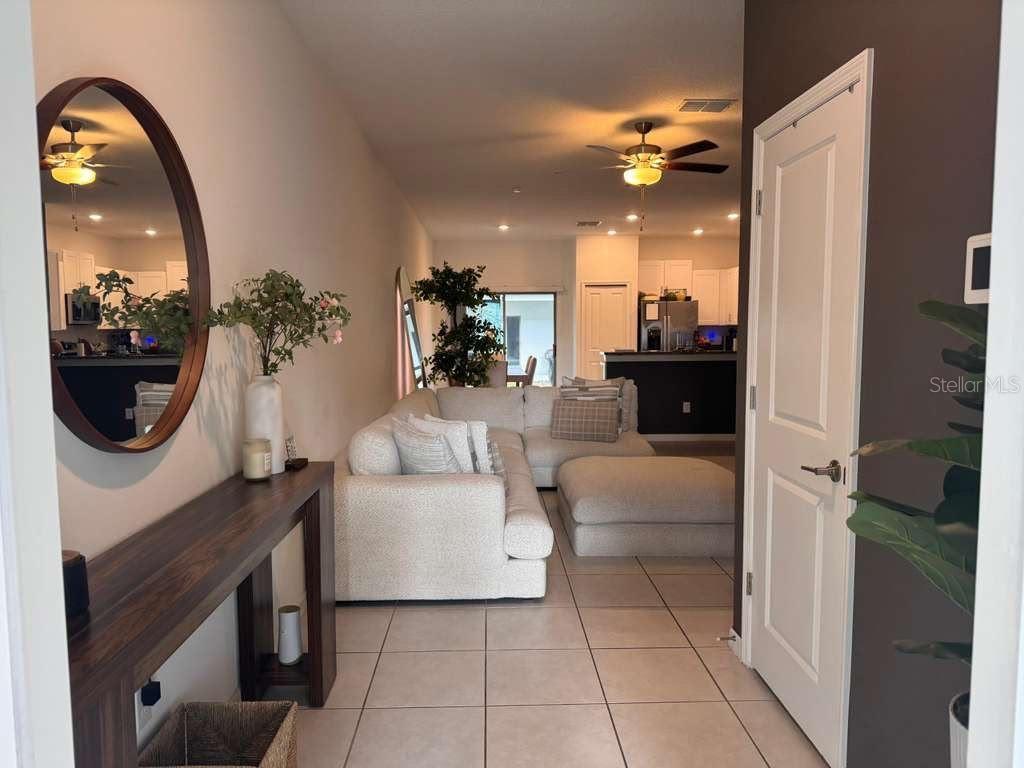 A view from a hallway into a living room with a sectional sofa and kitchen — 8339 BIRCH HAVEN LANE, NEW PORT RICHEY, FL