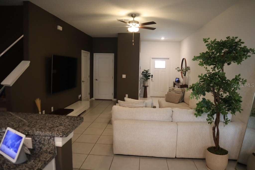 A living room features a white sectional sofa, a wall-mounted television, and a ceiling fan — 8339 BIRCH HAVEN LANE, NEW PORT RICHEY, FL