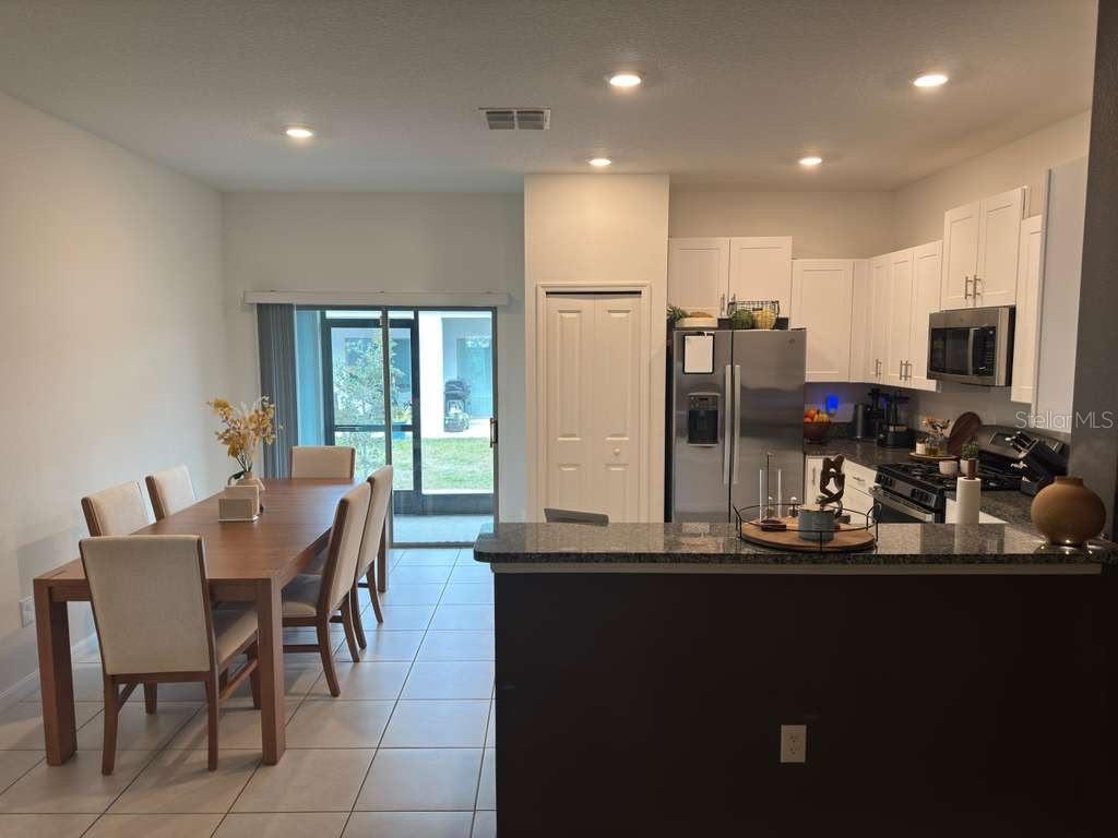 A dining area with a wooden table and chairs sits adjacent to an open kitchen — 8339 BIRCH HAVEN LANE, NEW PORT RICHEY, FL