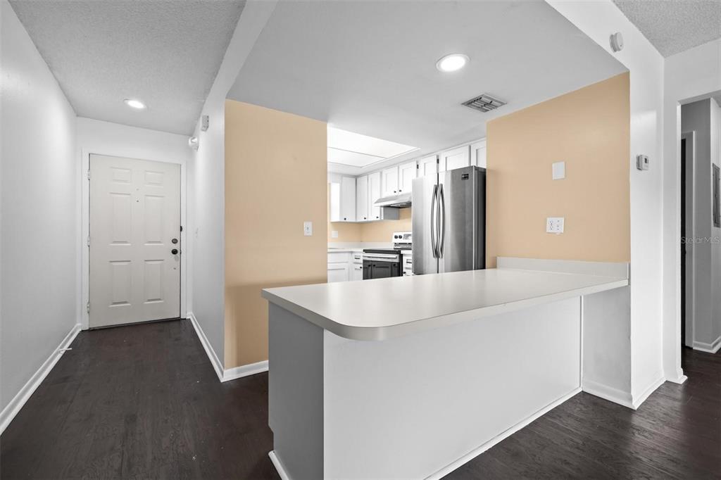 A kitchen with white cabinets and stainless steel appliances overlooks a breakfast bar — 6045 TOPHER TRAIL UNIT 24-C, MULBERRY, FL