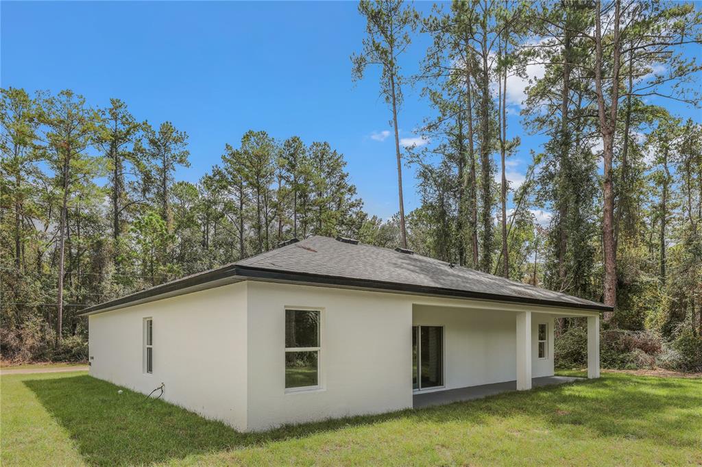 The exterior of a white, single-story house with a covered patio and a hip roof — 7833 SW 148TH STREET, OCALA, FL