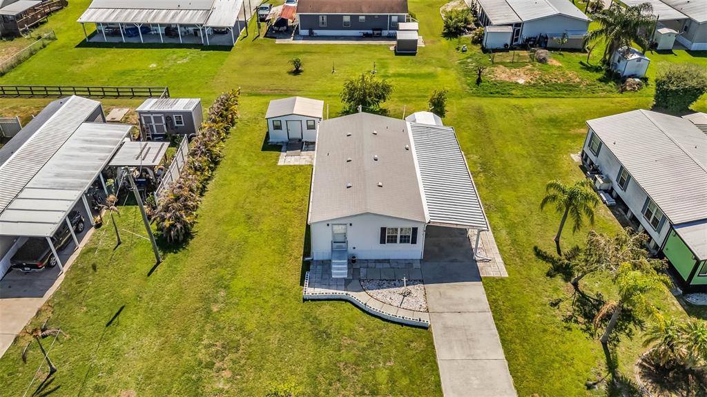 An aerial view shows a manufactured home with a metal roof, carport, and small shed — 11710 SW ORANGE AVENUE, ARCADIA, FL