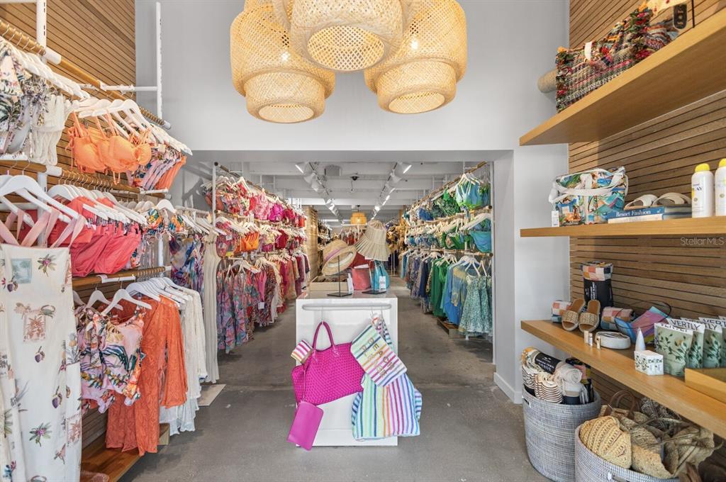 A retail boutique features racks of colorful clothing, woven light fixtures, and wooden display shelves — 331 JOHN RINGLING BOULEVARD UNIT 101, SARASOTA, FL