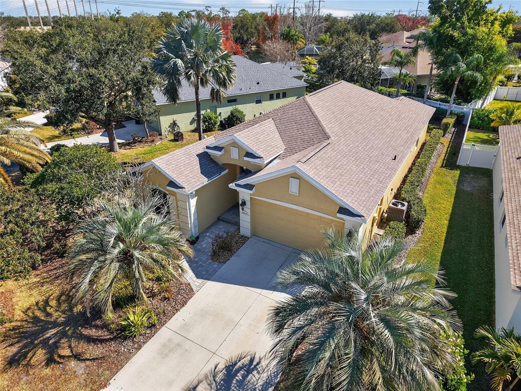 An aerial view shows a single-story house with a tan exterior and a shingled roof — 8124 TABBYSTONE PLACE, BRADENTON, FL