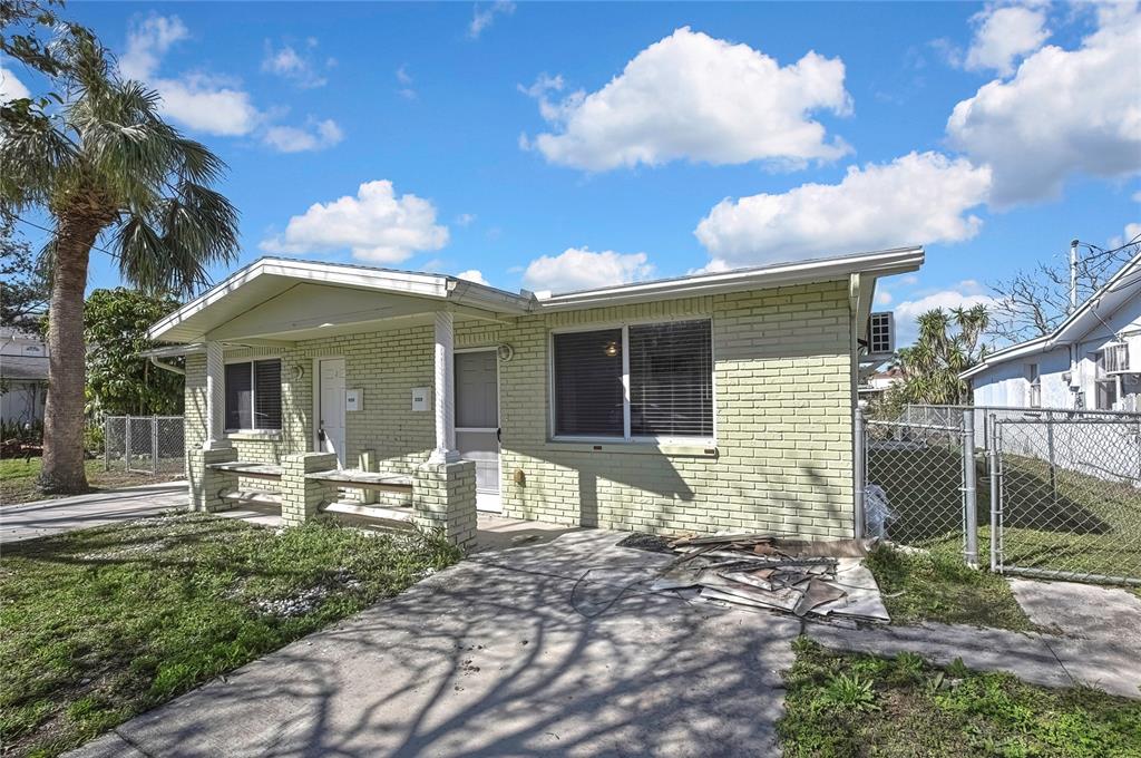 A single-story light green brick duplex with a concrete driveway and a chain-link fence — 12527 1ST ISLE, HUDSON, FL
