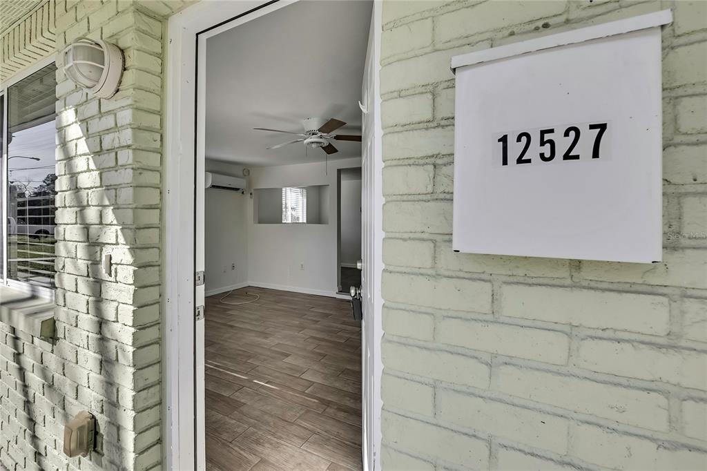 A view through an open doorway into a room with wood-look flooring and a ceiling fan — 12527 1ST ISLE, HUDSON, FL