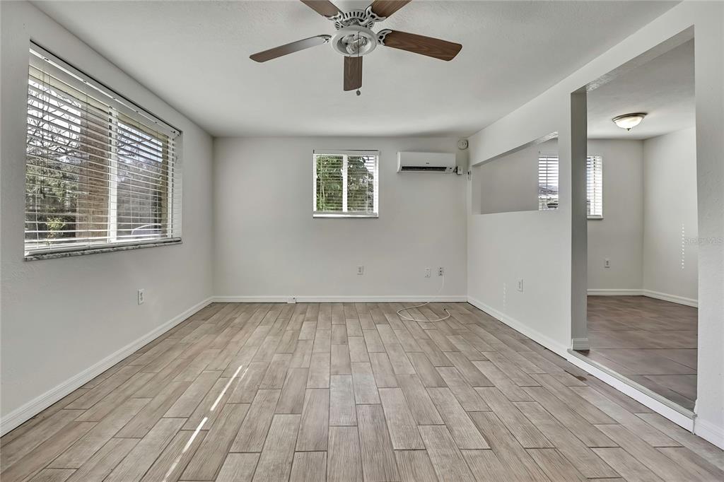 An empty room features light wood-look tile flooring, a ceiling fan, and a wall-mounted air conditioner — 12527 1ST ISLE, HUDSON, FL