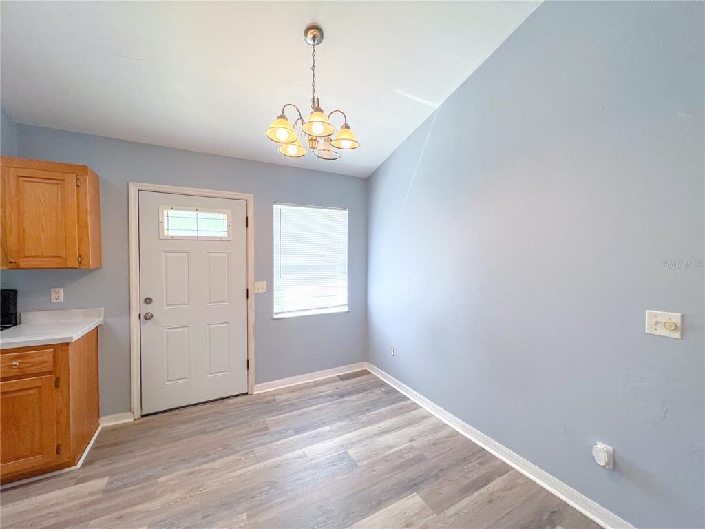 A dining area features light blue walls, wood-look flooring, a chandelier, and a white door — 24535 NW 189TH AVENUE, HIGH SPRINGS, FL