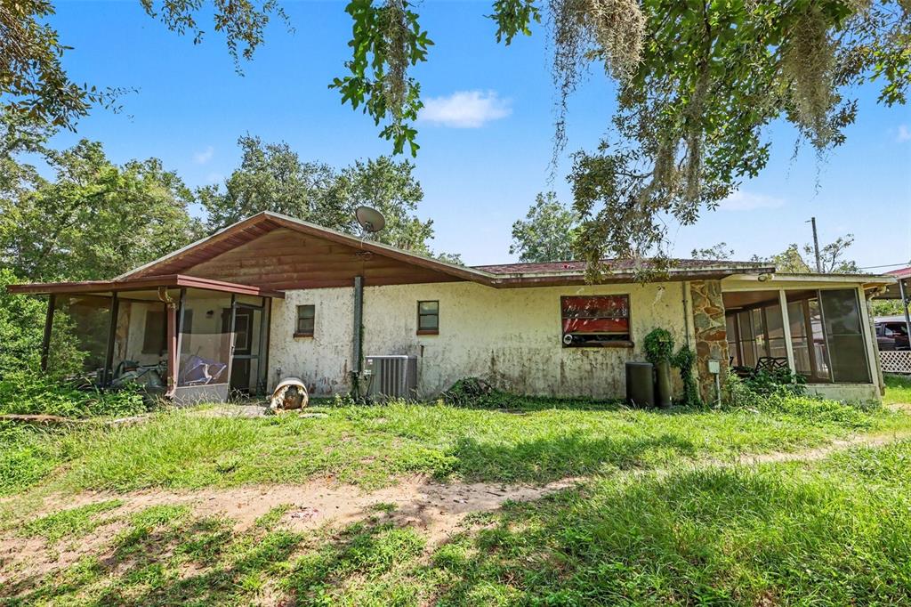 The exterior of a single-story house with a screened porch, stone accents, and overgrown yard — 4611 W OLD CITRUS ROAD, LECANTO, FL