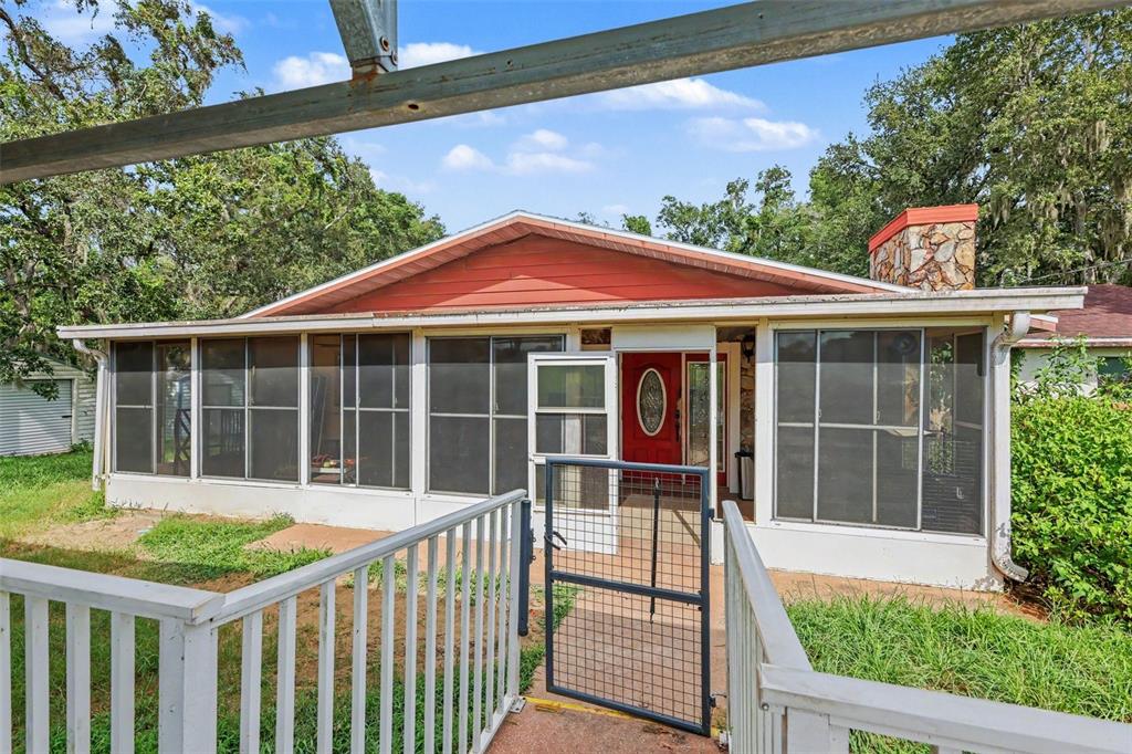 A house exterior features a screened-in porch, a red front door, and a stone chimney — 4611 W OLD CITRUS ROAD, LECANTO, FL