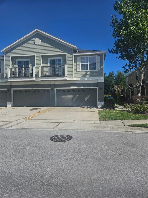 A two-story townhouse with light green siding, two balconies, and two attached garage doors — 1917 ESTANCIA CIRCLE, KISSIMMEE, FL