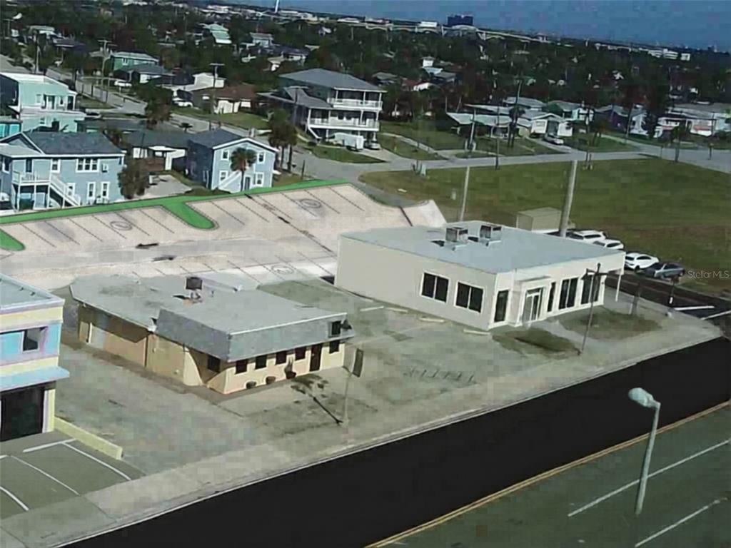 An aerial view shows two commercial buildings with parking lots in a coastal neighborhood — 2000 S ATLANTIC AVENUE, DAYTONA BEACH, FL