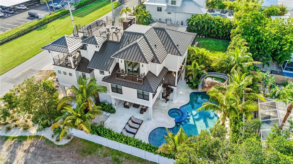 An aerial view of a multi-story house with a metal roof, pool, and rooftop deck — 171 MCKINLEY DRIVE, SARASOTA, FL