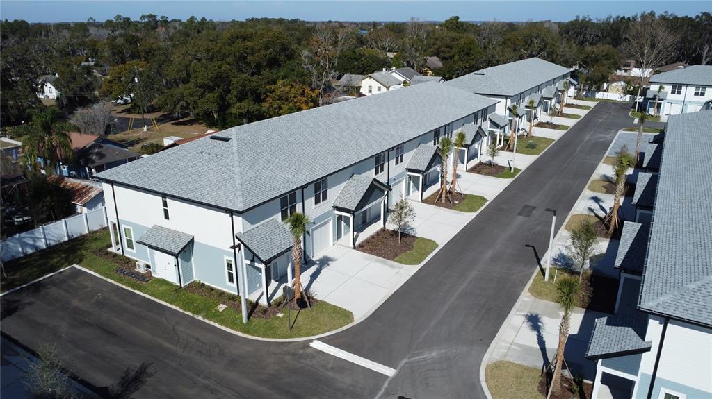 An aerial view shows a row of modern townhouses with gray roofs and paved driveways — 1075 E CAROLINE STREET, TAVARES, FL