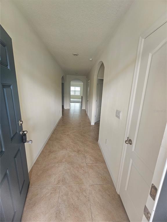 A tiled entryway hallway leads to an arched doorway with a view of a window — 1504 FOX SQUIRREL DRIVE, DAVENPORT, FL