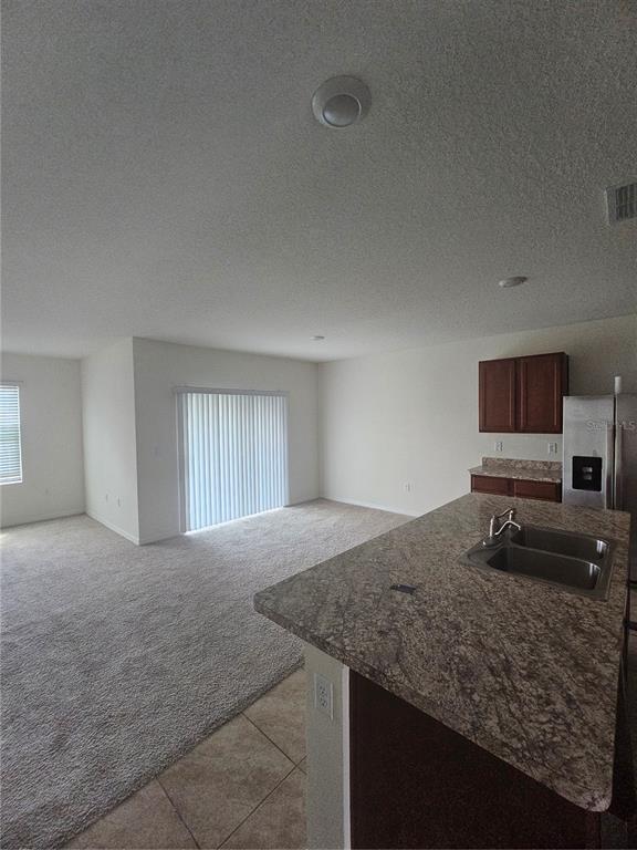 A kitchen with granite countertops and a sink overlooks an open living area with carpet — 1504 FOX SQUIRREL DRIVE, DAVENPORT, FL
