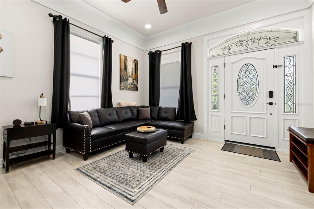 A living room features a black sectional sofa, a matching ottoman, and a white front door — 2526 W UNION STREET, TAMPA, FL