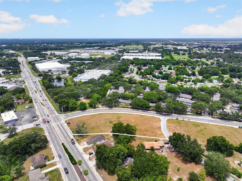 An aerial view shows a vacant lot bordered by a road and residential properties — 14TH STREET W, LAKELAND, FL
