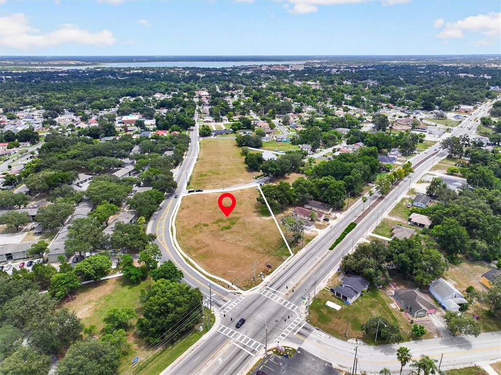 An aerial view shows a vacant, triangular lot marked with a red pin near roads — 14TH STREET W, LAKELAND, FL