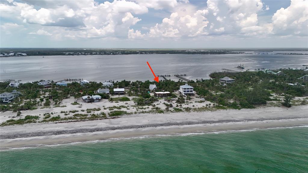 An aerial view shows a coastal property with several houses nestled among trees near the beach — 9144 CARTER ST, PLACIDA, FL