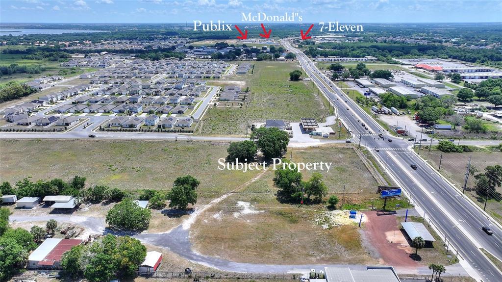 An aerial view shows a vacant lot adjacent to a highway with nearby commercial businesses — 75 SAGE ROAD, WINTER HAVEN, FL