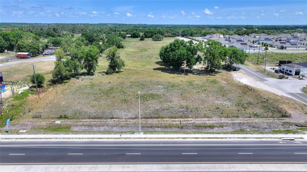 An aerial view shows a vacant, grassy lot situated next to a paved road — 75 SAGE ROAD, WINTER HAVEN, FL
