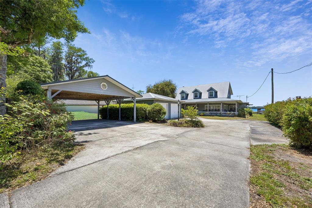 A concrete driveway leads to a detached carport and a two-story house with dormers — 7430 SW COUNTY ROAD 18, HAMPTON, FL