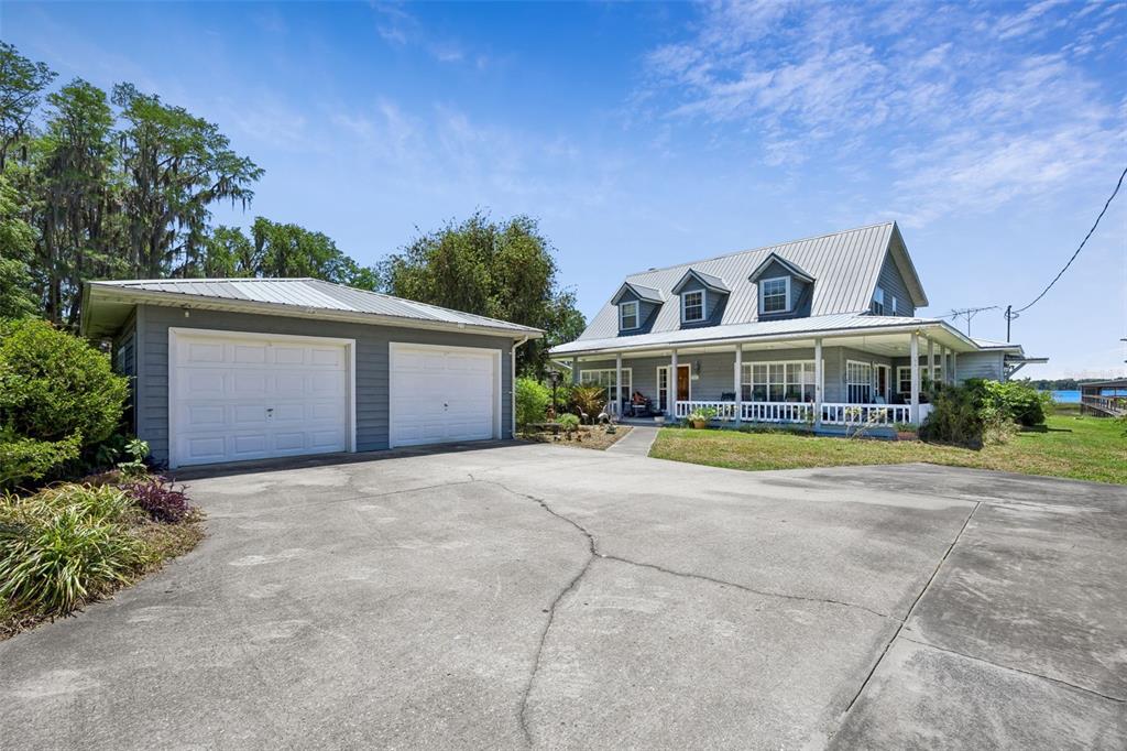 A gray two-story house with a metal roof and detached garage sits on a lot — 7430 SW COUNTY ROAD 18, HAMPTON, FL