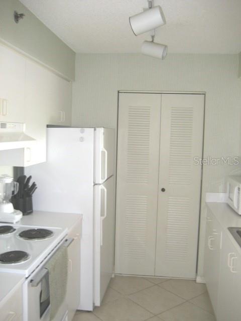 A kitchen features white appliances, white cabinets, a louvered closet door, and light-colored floor tiles — 19655 E COUNTRY CLUB DRIVE UNIT 6403, AVENTURA, FL