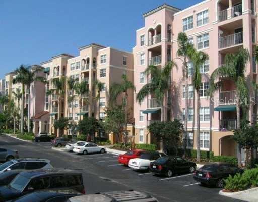 An exterior view of a multi-story pink apartment building with a parking lot in front — 19655 E COUNTRY CLUB DRIVE UNIT 6403, AVENTURA, FL