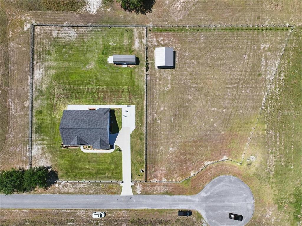 An aerial view shows a house with a driveway and two outbuildings on a fenced lot — 10172 98TH PATH, LIVE OAK, FL
