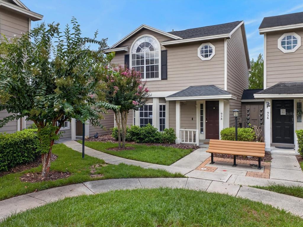 A two-story tan townhouse with a brown front door, arched window, and a wooden bench — 958 SYKES COURT UNIT 104, ORLANDO, FL