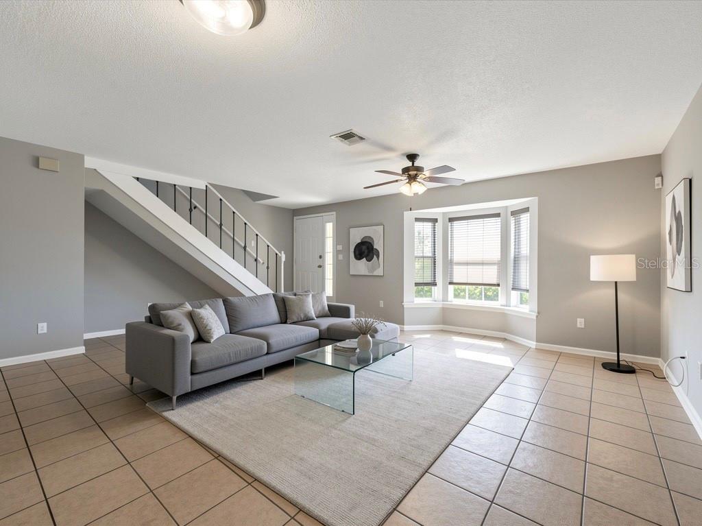A living room features a gray sectional sofa, a glass coffee table, and a staircase — 958 SYKES COURT UNIT 104, ORLANDO, FL