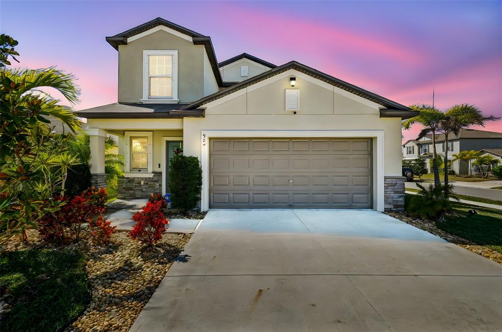 A two-story suburban house with a tan stucco exterior, a two-car garage, and landscaping — 984 OLIVE CONCH STREET, RUSKIN, FL