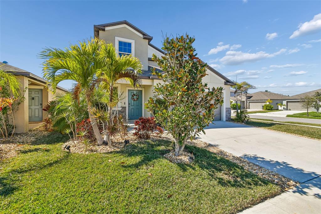 A two-story suburban house with a teal front door, palm trees, and a concrete driveway — 984 OLIVE CONCH STREET, RUSKIN, FL