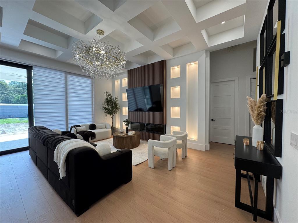 A modern living room features a coffered ceiling, a slatted wood fireplace wall, and chandelier — 8143 WHEYSTONE DRIVE, WEBSTER, FL