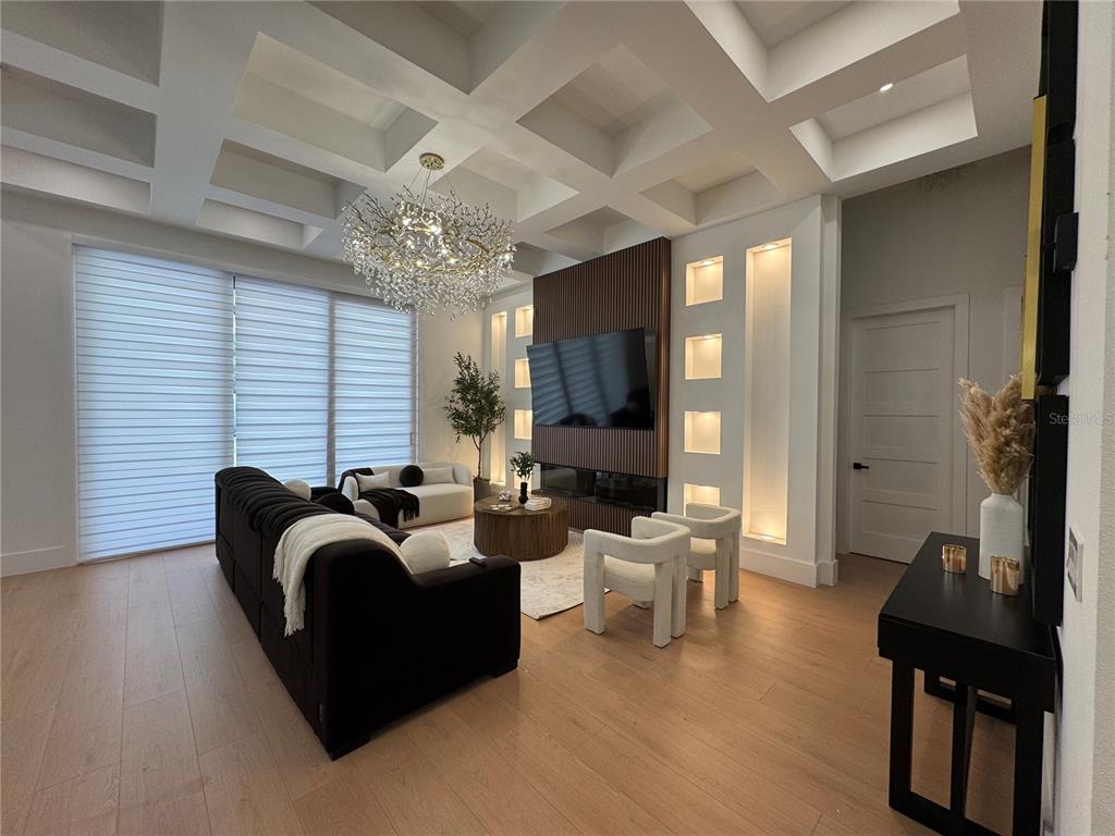 A modern living room features a coffered ceiling, a wood-slatted accent wall, and large windows — 8143 WHEYSTONE DRIVE, WEBSTER, FL