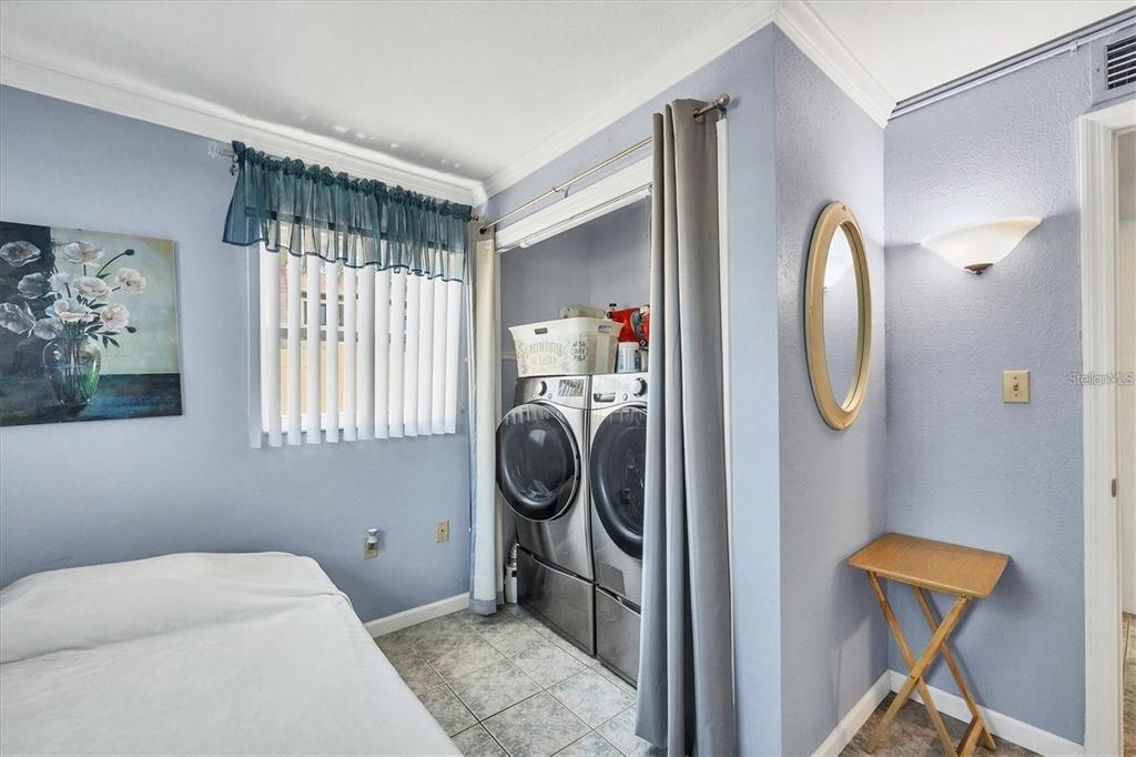 A bedroom features light blue walls, a tile floor, and a laundry closet with appliances — 460 BASE AVENUE E UNIT 113, VENICE, FL