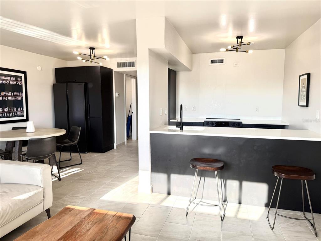 A kitchen features dark cabinets, a white countertop with an integrated sink, and tile flooring — 2525 W BAY DRIVE UNIT C34, LARGO, FL