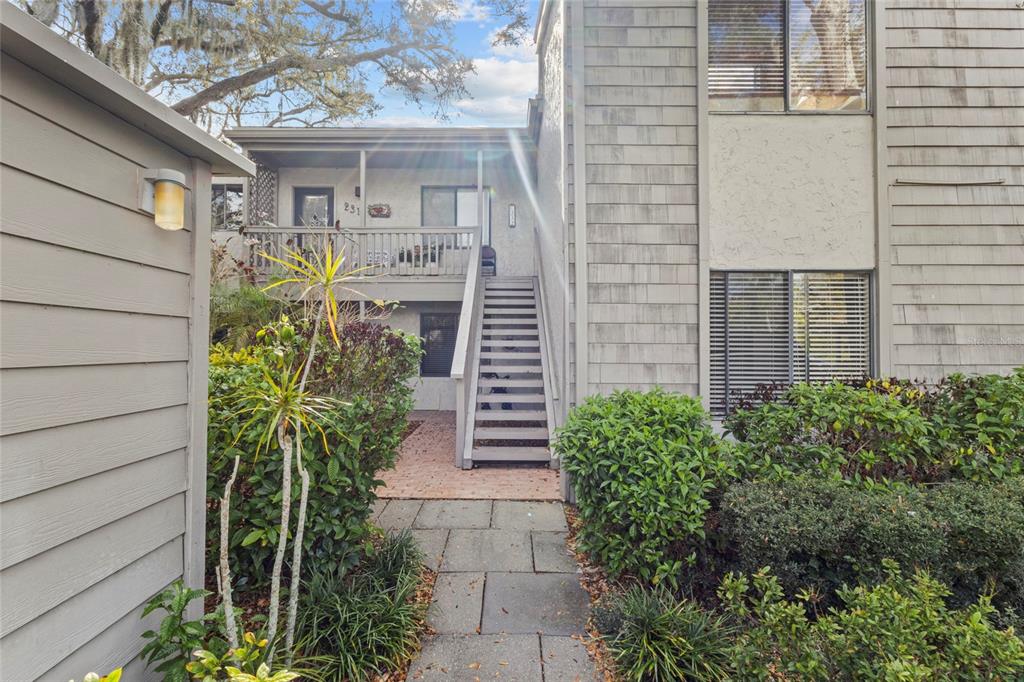 A wooden staircase leads to the second-story balcony of a multi-story residential building — 1633 BOATHOUSE CIRCLE UNIT 232, SARASOTA, FL